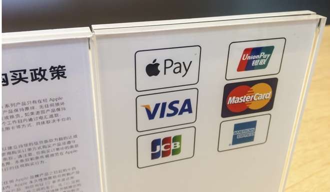 Retail sign at an Apple store in Shanghai explaining that purchases can be made using Apple Pay, as well as other formats. Photo: AFP