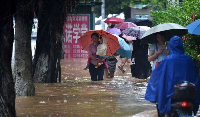People walk in water in flooded streets in Haikou, capital of south China's Hainan Province due to rains from typhoon 