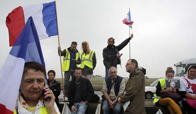 Demonstrators hold French flags as truckers and others block the highway near Calais on Monday. Photo: AP