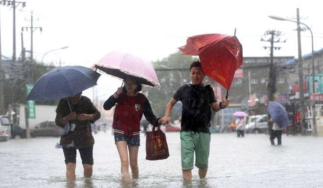 People walk along a flooded street in Beijing in July. Photo: AFP