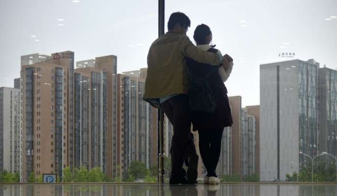 A couple look out in front of a window at mall in Beijing. Photo: AFP