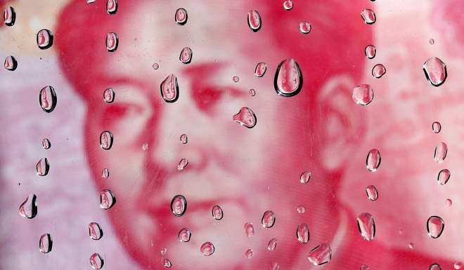 A portrait of former Chinese leader Mao Zedong on a yuan banknote is reflected in water droplets. Photo: Reuters