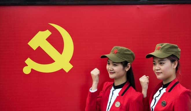 Chinese tourists pose in front a flag of the Communist Party in Mao’s hometown, Shaoshan. Photo: AFP