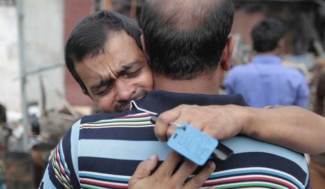 A factory employee is comforted near the site. Photo: AP