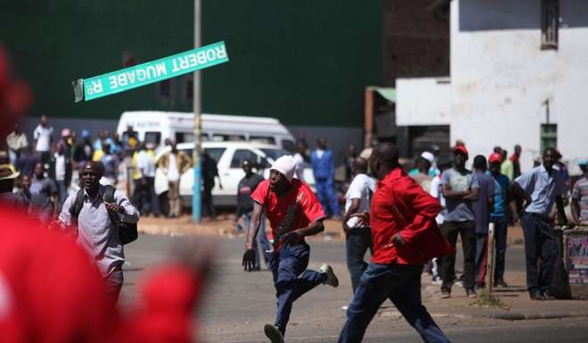 This file photo taken on August 26 shows a protester throwing a street sign with President Robert Mugabe name on it as Zimbabwe opposition supporters clash with police during a protest march for electoral reforms in Harare. Photo: AFP