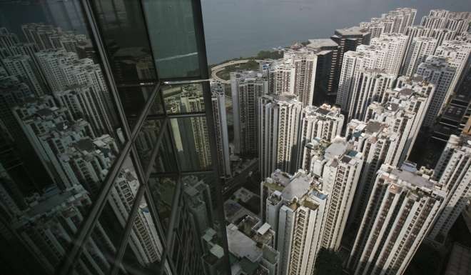 Residential blocks reflected in the glass panes of a business tower in Hong Kong, symbols of the twin engines that keep the city’s economy humming. Photo: Reuters