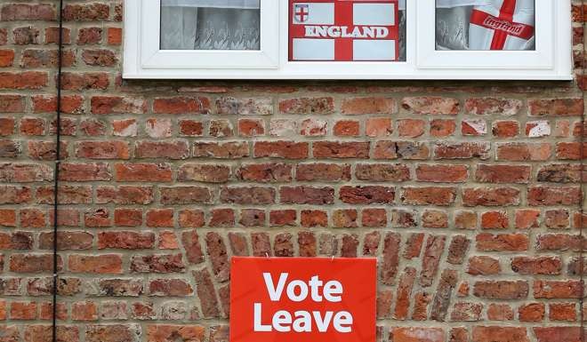 St George’s Cross flags hang in the windows as a poster makes the public sentiment clear in Redcar, northeast England on June 27, days after the UK voted to leave the European Union. Photo: AFP