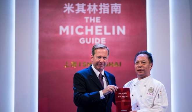 Michelin Guides director Michael Ellis and master chef of Canton 8 Jie Ming Jian hold a copy of the Michelin guide to Shanghai, which awards two stars to the restaurant. Canton 8 is the least expensive two-Michelin-star restaurant in the world. Photo: AFP