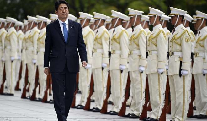 Japanese Prime Minister Shinzo Abe reviews an honour guard at the Defence Ministry in Tokyo on September 12. The IMF has admitted his Abenomics economic model is not working. Photo: EPA