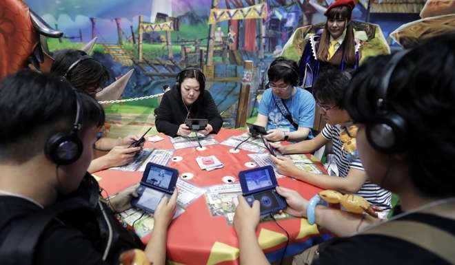Attendees play video games on Nintendo's 3DS LL in the Capcom booth at the Tokyo Game Show 2016. Photo: Bloomberg