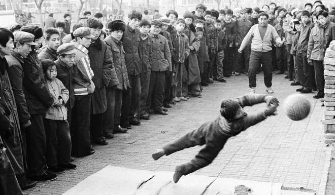 A boy and his father display their soccer skills on a roadside in Beijing in 1981. Photo: Reuters