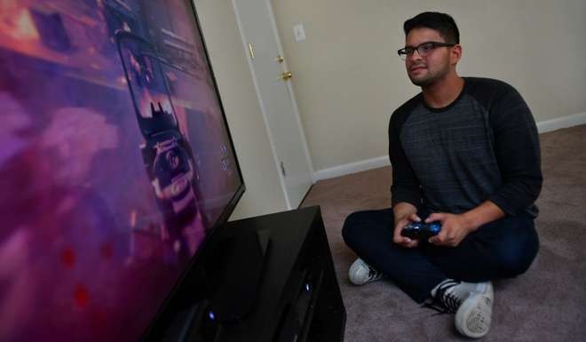 Danny Izquierdo enjoys playing video games on all platforms. He often plays with friends through a big screen TV, as shown, but is just as adept at gaming on a laptop or smartphone. Photo: Michael S. Williamson/The Washington Post