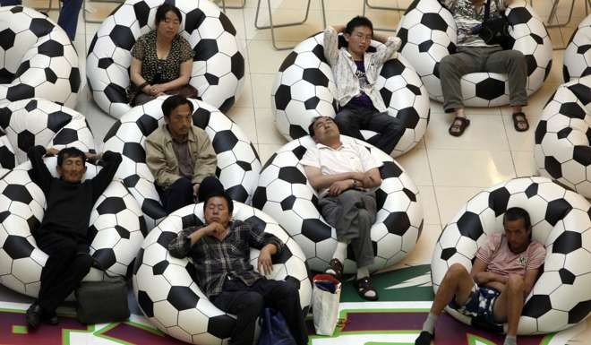 Chinese residents rest on chairs that look like footballs in June 2010 near a screen showing reruns of World Cup matches. Photo: AP