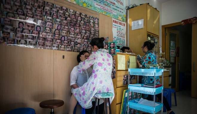 Li Chau-jing (centre) and an assistant pluck customers’ eyebrows at her shop in Sham Shui Po. Clients believe slight changes to their brows can improve their luck. Photo: AFP