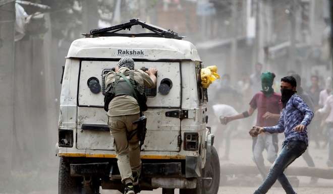 Demonstrators try to hurl stones at an Indian police vehicle during a protest in Srinagar. Photo: Reuters