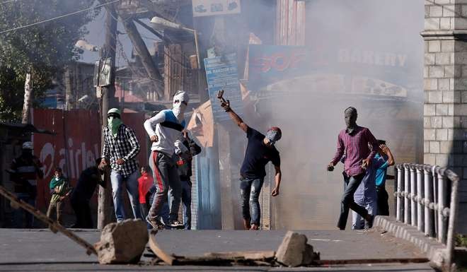 Demonstrators hurl stones towards Indian policemen during a protest in Srinagar. Photo: Reuters
