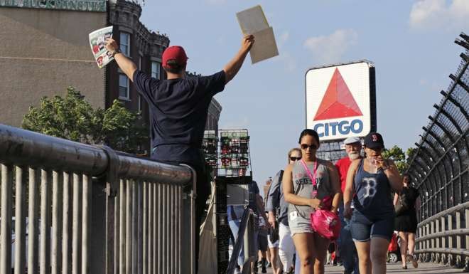 A hawker sells programmes as fans walk across the Brookline Avenue Bridge from Kenmore Square to a baseball game at Fenway Park in Boston. Massachusetts officials are moving to name the bridge in honour of retiring Boston Red Sox slugger David Ortiz. Photo: AP