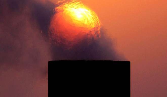 Smoke rises from an oil pipe at sunset in the desert oil field of Sakhir, Bahrain. Photo: AP