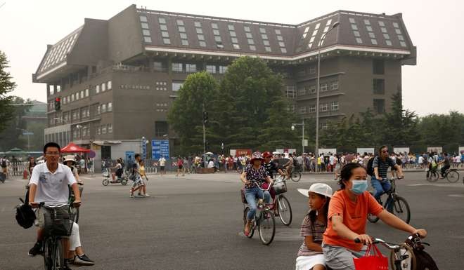 People cycle past a building in Peking University in Beijing. Photo: Reuters
