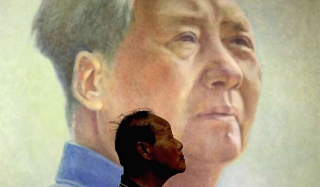 A man stands in front of a portrait of Mao Zedong at an art exhibition in Beijing. Photo: AP