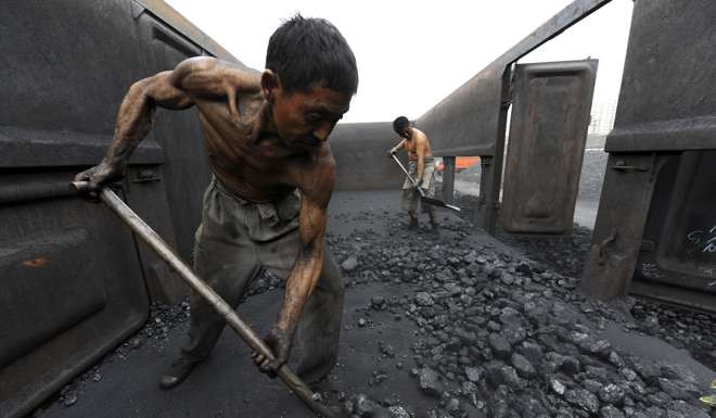 Workers unload coal at a storage site along a railway station in Hefei, Anhui province. Photo: Reuters