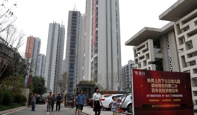 A saleswoman leads people to a new residential building in Jinan, one of the mainland cities where sales surged during golden week. Photo: Xinhua