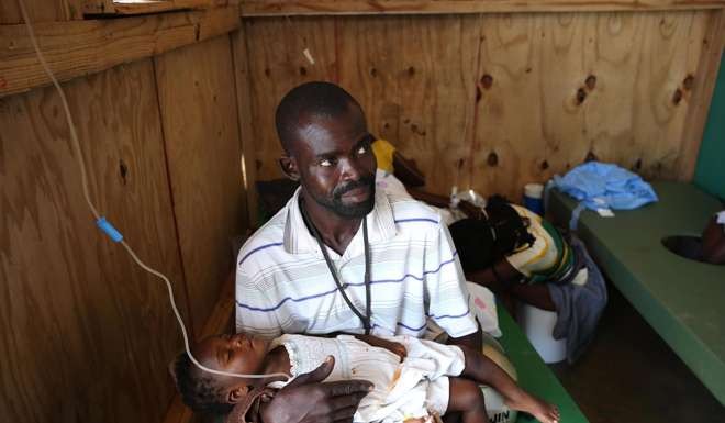 A man holds a child sick with cholera who receives medical assistance at Saint Antoine hospital in Jeremi, Haiti. Photo: EPA