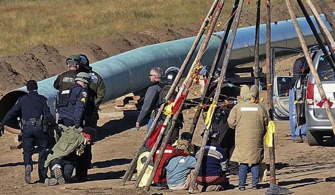 Law enforcement officers, left, drag a person from a protest against the Dakota Access Pipeline, near the town of St Anthony in North Dakota on Monday. Photo: AP