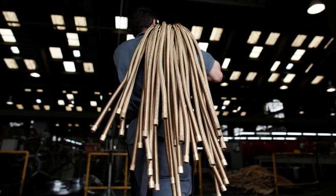 An employee carries copper hoses at the Sociedade Paulista de Tubos Flexiveis (SPTF) metallurgical company which manufactures flexible metal hoses, in Sao Paulo, Brazil. Photo: Reuters