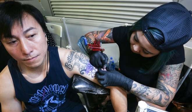 Tattoo artist Jennifer Neoh (right) demonstrating her skills at the convention. Photo: Jonathan Wong