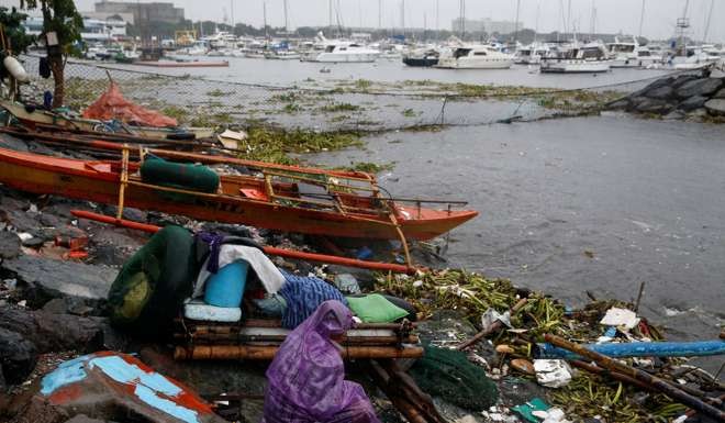 A fisherman stays near his boat docked along the shore overlooking yachts in Manila bay after Typhoon Sarika slammed central and northern Philippines. Photo: Reuters