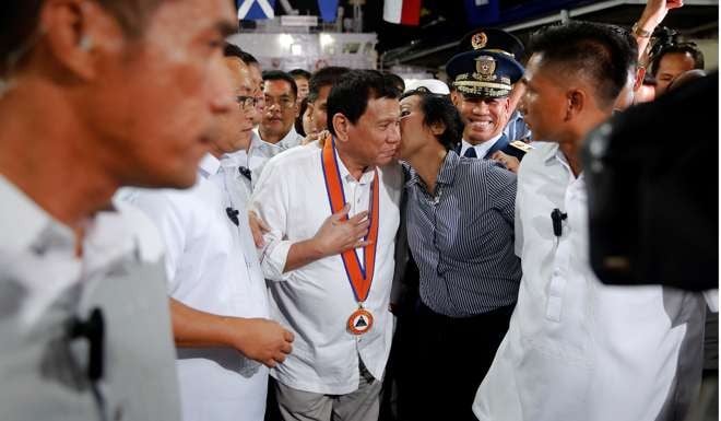 President Rodrigo Duterte is kissed by a woman as he attends a ceremony marking the anniversary of the Philippines Coast Guard in Manila. Duterte knows that the Philippines is a booming emerging market, and he’s got two avid suitors in China and the US. Photo: Reuters