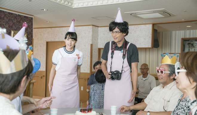 A scene from the film in which Mizuki Yamamoto’s character, Atsuko, volunteers at a nursing home alongside a character played by Goro Inagaki (centre, with camera).