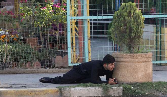 A Kurdish security personnel takes cover at a site of an attack by Islamic State militants in Kirkuk. Photo: Reuters