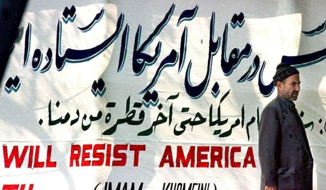 An Iranian man stands in front of an anti-American banner hung at Tehran University. Photo: AP