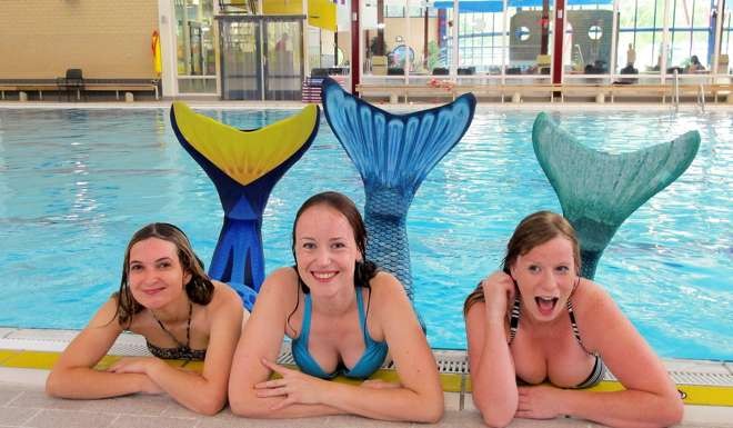 Three women dressed up as mermaids pose by a pool at a mermaid training school in Zeist. AFP