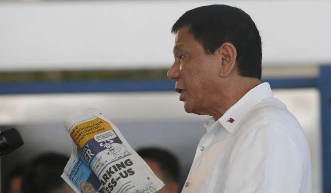 Philippine President Rodrigo Duterte holds a copy of a the Philippine Daily Inquirer with the headline: ‘Duterte sparking international distress-US’ during a news conference prior to boarding his flight for a three-day official visit to Japan. Photo: AP