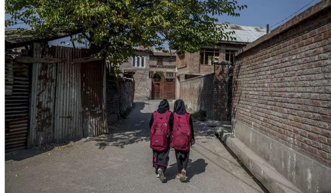 Iqra and her cousin Muskan walk back home after attending an ad-hoc learning centre set up in a local mosque in Srinagar. Photo: AP