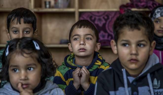 Kashmiri children listen to their teacher as they attend an ad-hoc learning centre. Photo: AP