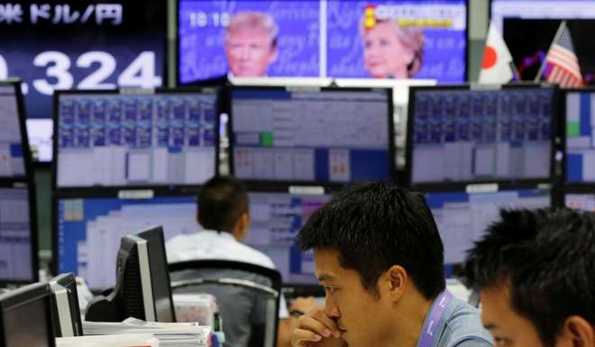 Employees of a foreign exchange trading company work near monitors displaying first U.S. presidential debate between U.S. Republican nominee Donald Trump and Democratic presidential nominee Hillary Clinton. Photo: Reuters