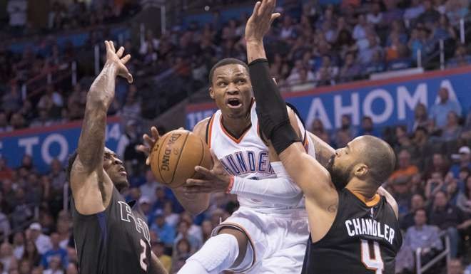 Russell Westbrook #0 of the Oklahoma City Thunder goes between Eric Bledsoe #2 of the Phoenix Suns and Tyson Chandler #4 AFP