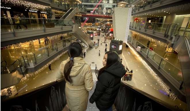 Shoppers ride an escalator in an upscale shopping mall in Beijing. As more goods are being consumed by wealthier people inside China, so less of China’s output is destined for export. Photo: AP