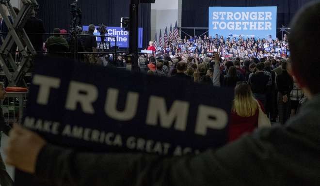 A supporter of Republican presidential candidate Donald Trump holds up a Trump campaign poster in the back of the room as Democratic presidential candidate Hillary Clinton speaks at Kent State University in Kent, Ohio. Photo: AP