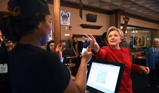 US Democratic presidential nominee Hillary Clinton takes the phone of an employee to have a picture taken at a restaurant in Cleveland, Ohio. Photo: AFP