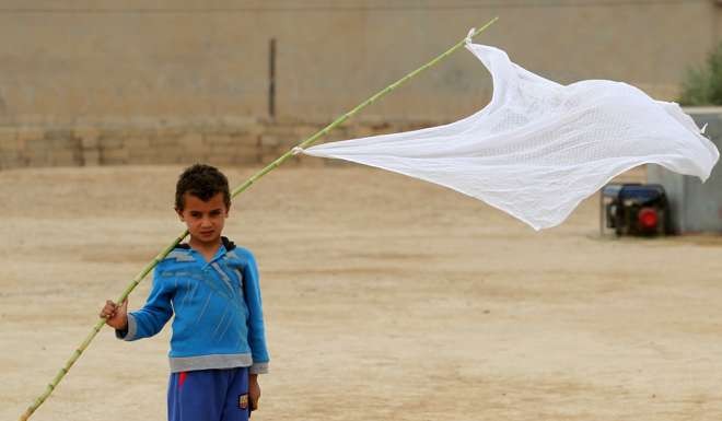 An Iraqi boy who was displaced from the village of Abu Shuwayhah, south of the jihadist-held Mosul, walks carrying a white flag as locals return to their village. Photo: AFP