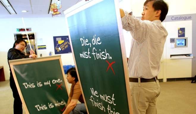 Library personnel set up posters promoting the use of correct spoken English in a library in Singapore. The country’s leaders have tried to suppress the use of Singlish. Photo: AP