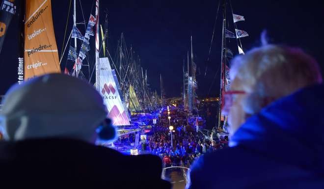 People look at class Imoca monohulls on November 4, 2016 in Les Sables-d'Olonne, western France, during the last week before the start of the Vendee Globe solo around-the-world sailing race. / AFP PHOTO / LOIC VENANCE