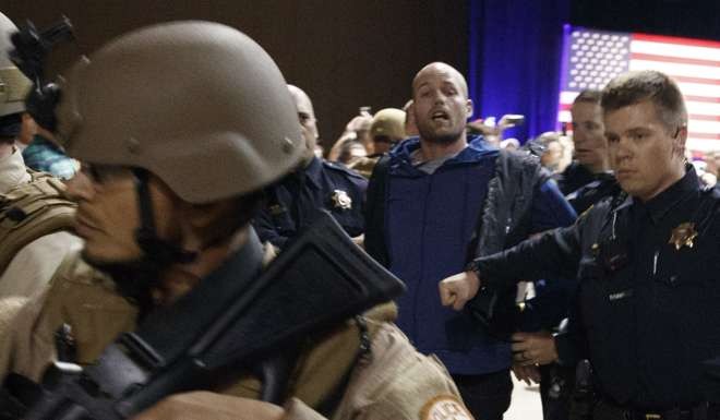 Austyn Crites, with blue sweater, is escorted by law enforcement officers moments after Trump was rushed offstage. Photo: AP