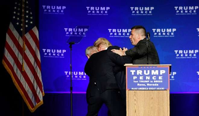 Trump is hustled off the stage by security agents. Photo: Reuters