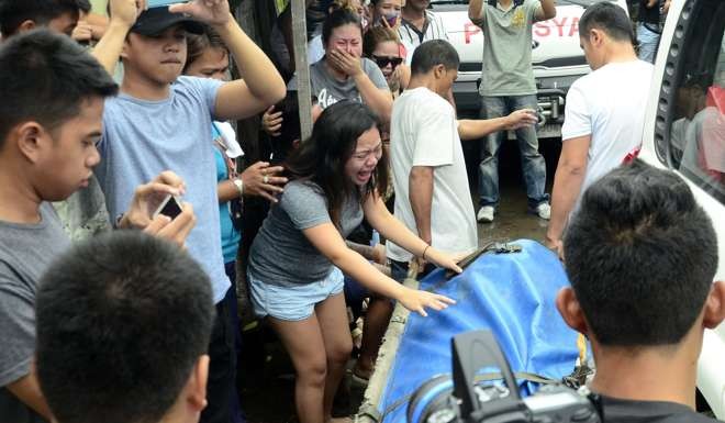 A relative of town mayor Rolando Espinosa cries over his body as it is carried away by funeral workers outside a prison facility where he was shot dead in his cell. Photo: EPA